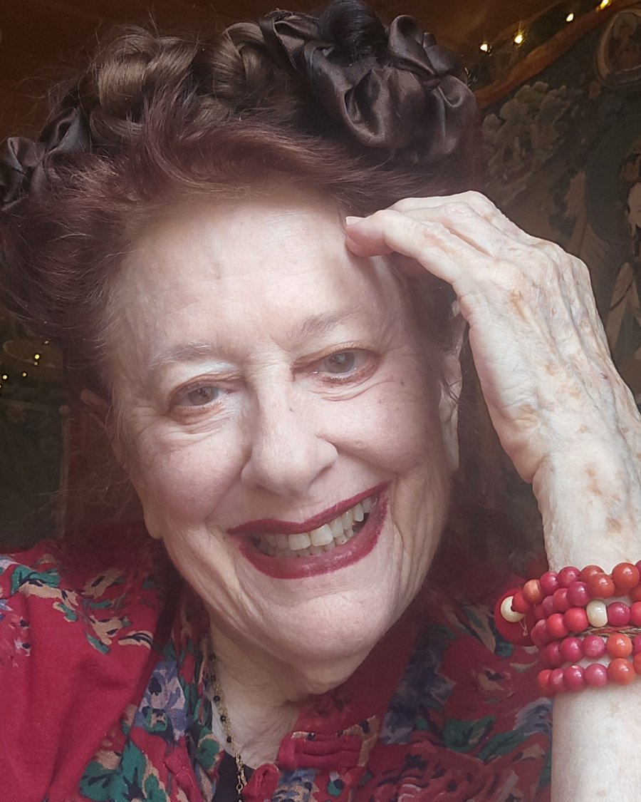 Jill Ansell at home, in a red floral jacket, smiling